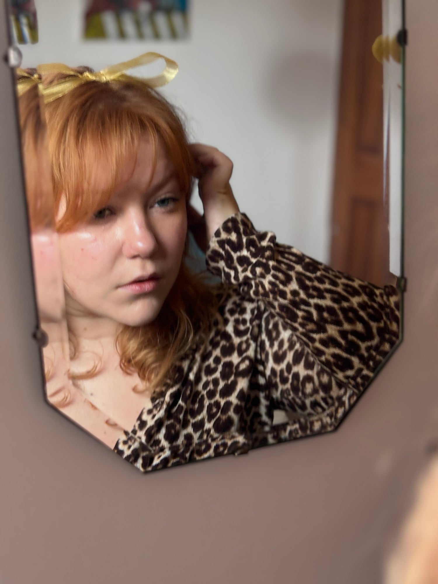 rachel, the owner looking into mirror with gold ribbon atop hair